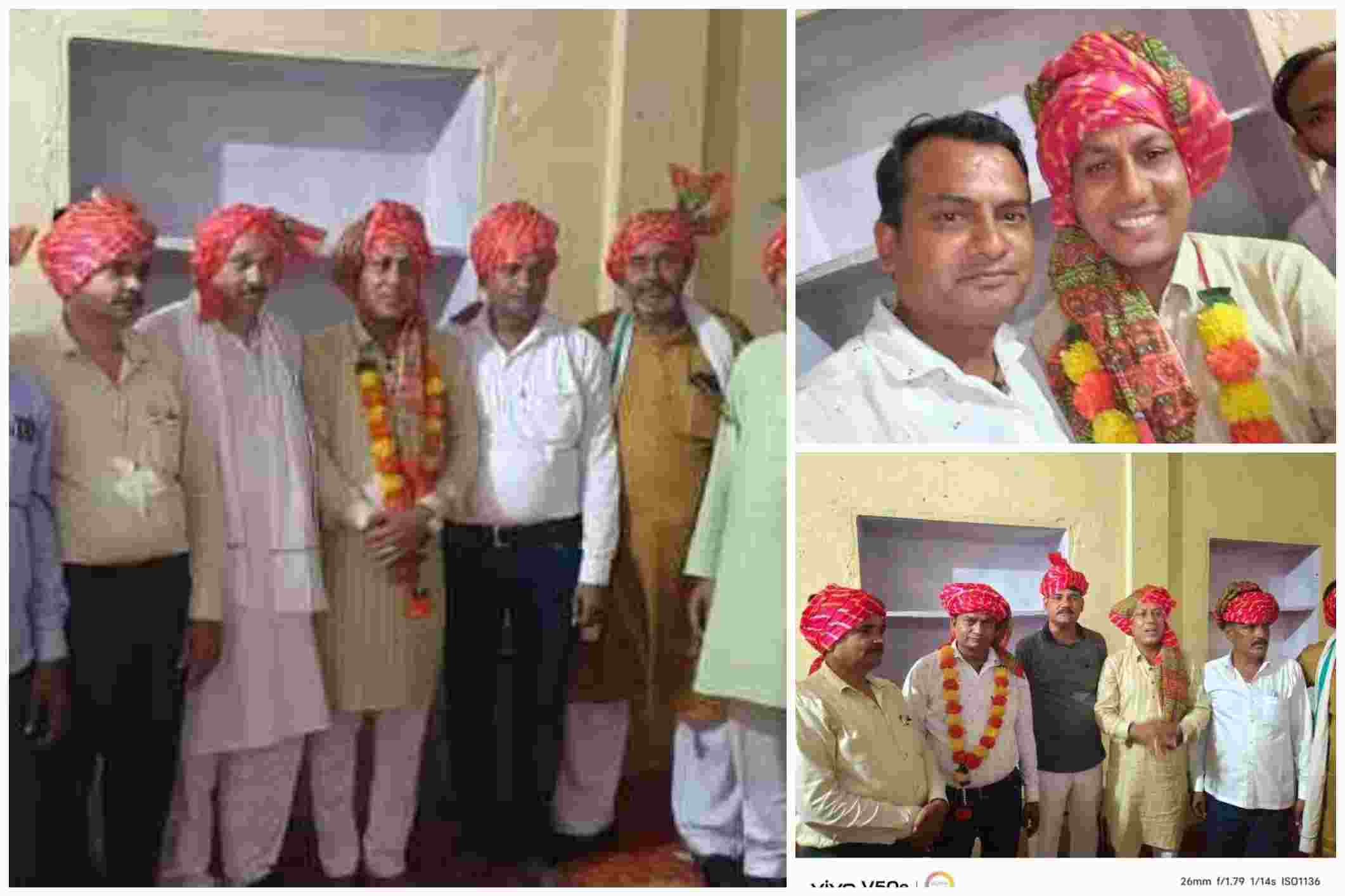 कई पुरुष पारंपरिक राजस्थानी साफा और माला पहनकर दीवार के सामने समूह में खड़े हैं