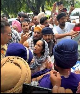 "सड़क पर पुलिसकर्मी और सिख व्यक्तियों की भीड़, मोबाइल से फोटो लेते लोग और विरोध की स्थिति नज़र आ रही है।"