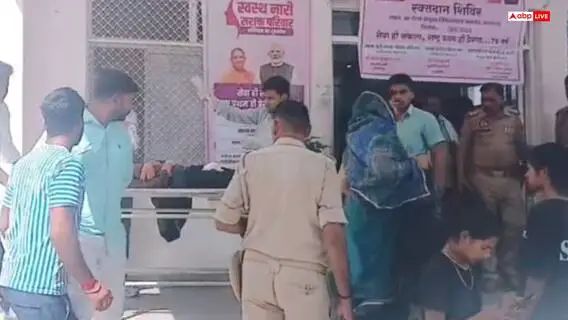 अस्पताल की इमरजेंसी के बाहर कई लोग, पुलिसकर्मी और एक स्टेचर पर मरीज दिखाई दे रहा है, आसपास कुछ महिलाएँ और पुरुष खड़े हैं।