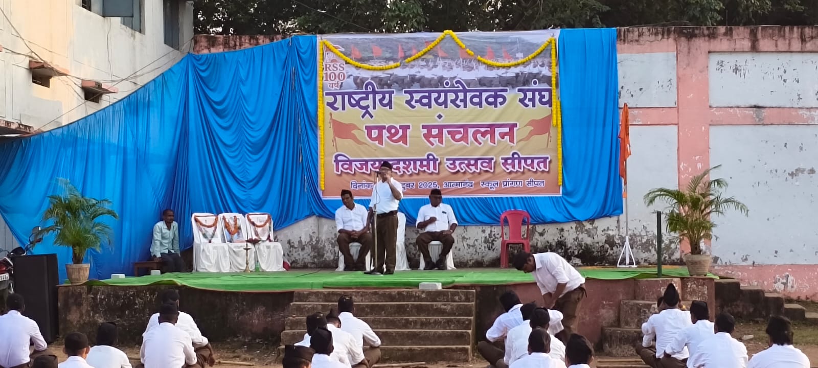 राष्ट्रीय स्वयंसेवक संघ सीपत के विजयादशमी और शताब्दी वर्ष उत्सव कार्यक्रम में पूर्ण गणवेश में बैठे स्वयंसेवक और मंच पर अतिथि वक्ता, विद्यालय प्रांगण में पथ संचलन आयोजन"