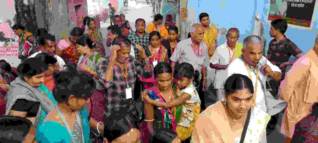 मंदिर परिसर में खड़े श्रद्धालु हाथ उठाकर अभिवादन कर रहे हैं।