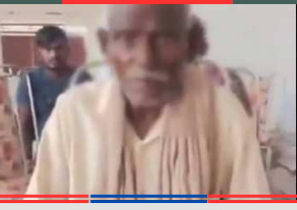 अस्पताल के वार्ड में बैठे बुजुर्ग व्यक्ति और पीछे अन्य मरीज