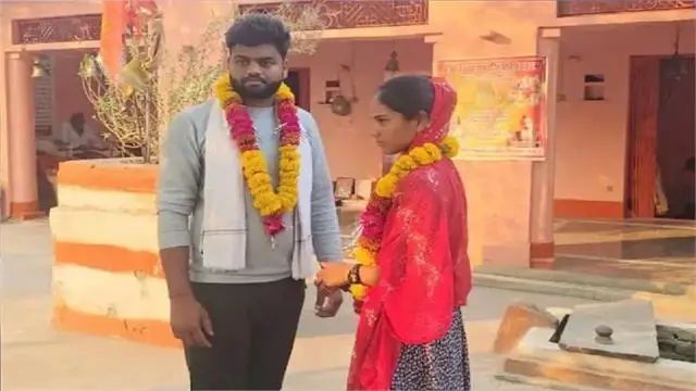 "एक पुरुष और महिला पारंपरिक पोशाक में विवाह के बाद हार के साथ खड़े हैं, उनके चेहरे धुंधले किए गए हैं। पृष्ठभूमि में एक भारतीय घर/मंदिर दिख रहा है।"