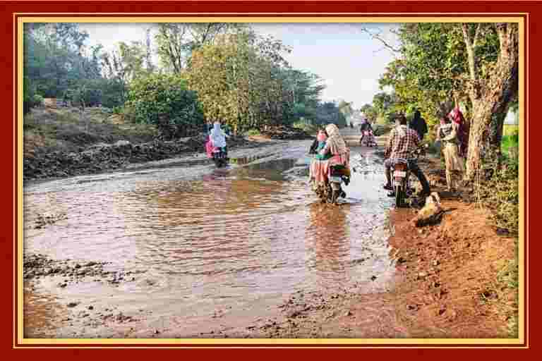 बारिश के बाद जलभराव से भरी सड़क पर पानी के बीच से गुजरते दुपहिया वाहन और राहगीर
