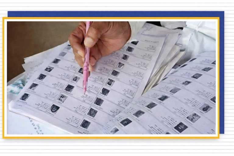 पंचायत चुनाव से पहले वोटर लिस्ट में नामों की जांच करते हुए मतदाता सूची पर पेन से इशारा करता अधिकारी