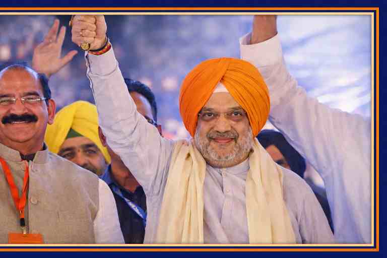 पंजाब की रैली में केसरी पगड़ी पहने केंद्रीय गृह मंत्री अमित शाह हाथ उठाकर कार्यकर्ताओं का अभिवादन करते हुए