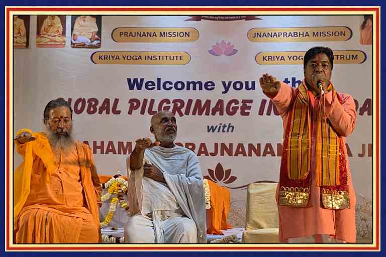 मंच पर तीन आध्यात्मिक गुरु बैठे और संबोधित करते हुए, वैश्विक तीर्थ यात्रा कार्यक्रम के बैकड्रॉप के साथ