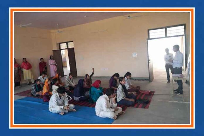 राजकीय महाविद्यालय कामवन में राजस्थान दिवस पर छात्र-छात्राएं फर्श पर बैठकर क्विज और शैक्षणिक गतिविधियों में भाग लेते हुए, शिक्षक सामने प्रस्तुति देते हुए